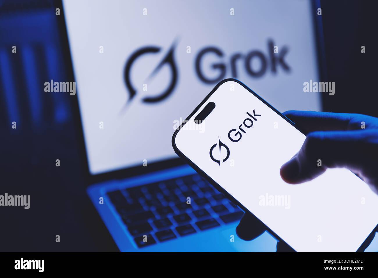 Izmir, Türkei - 21. Januar 2026: Hand hält ein modernes Smartphone mit geöffneter Grok AI-App auf dem Bildschirm, moderner Laptop im Hintergrund zeigt auch die Grok-Schnittstelle Stockfoto