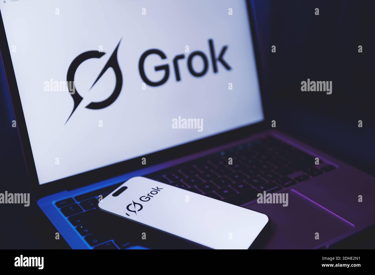 Izmir, Türkei - 21. Januar 2026: Foto eines Laptops mit Grok AI Logo auf weißem Hintergrund, modernes Smartphone auf der Tastatur, das auch Gro zeigt Stockfoto