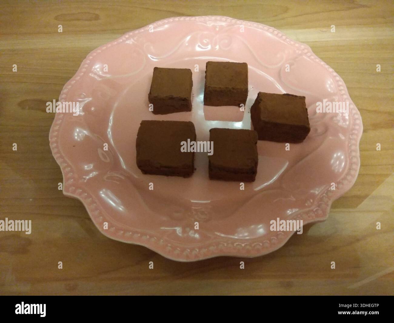 Schokoladen-Brownies serviert auf einem rosa Keramikteller Stockfoto