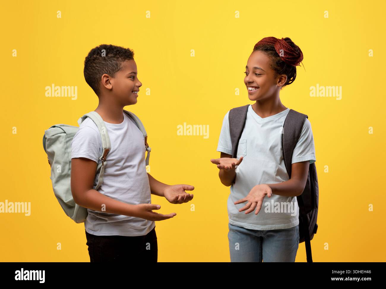 Glückliche afroamerikanische Schüler, die sich auf Gelb unterhalten Stockfoto