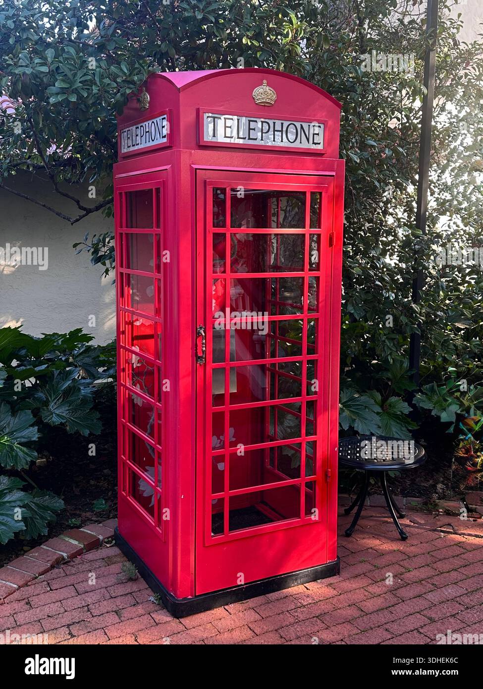 Ikonische rote britische Telefonzelle im Garten - Smartphone-aufgenommenes Stockfoto
