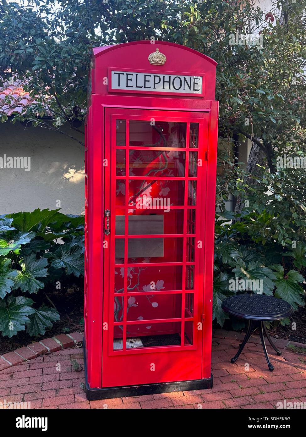 Ikonische rote britische Telefonzelle im Garten - Smartphone-aufgenommenes Stockfoto