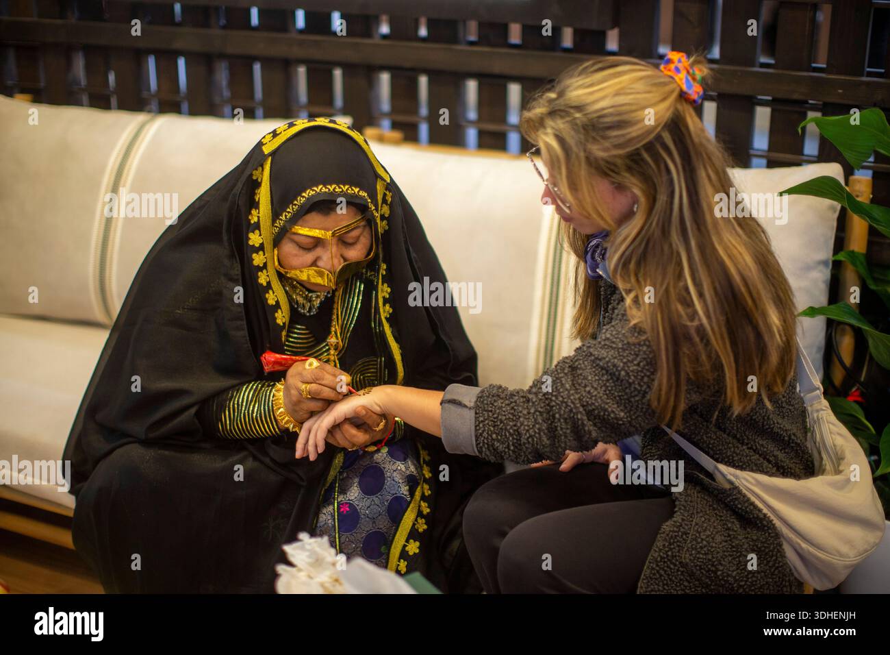 Eine Frau malt ein Henna-Tattoo auf die Hand eines Besuchers am Stand von Abu Dhabi während der Feier der Internationalen Tourismusmesse (FITUR) 2026 in Madrid. Mexiko ist das Gastland der 46. Ausgabe von FITUR, an der mehr als 161 Länder teilnehmen. Stockfoto