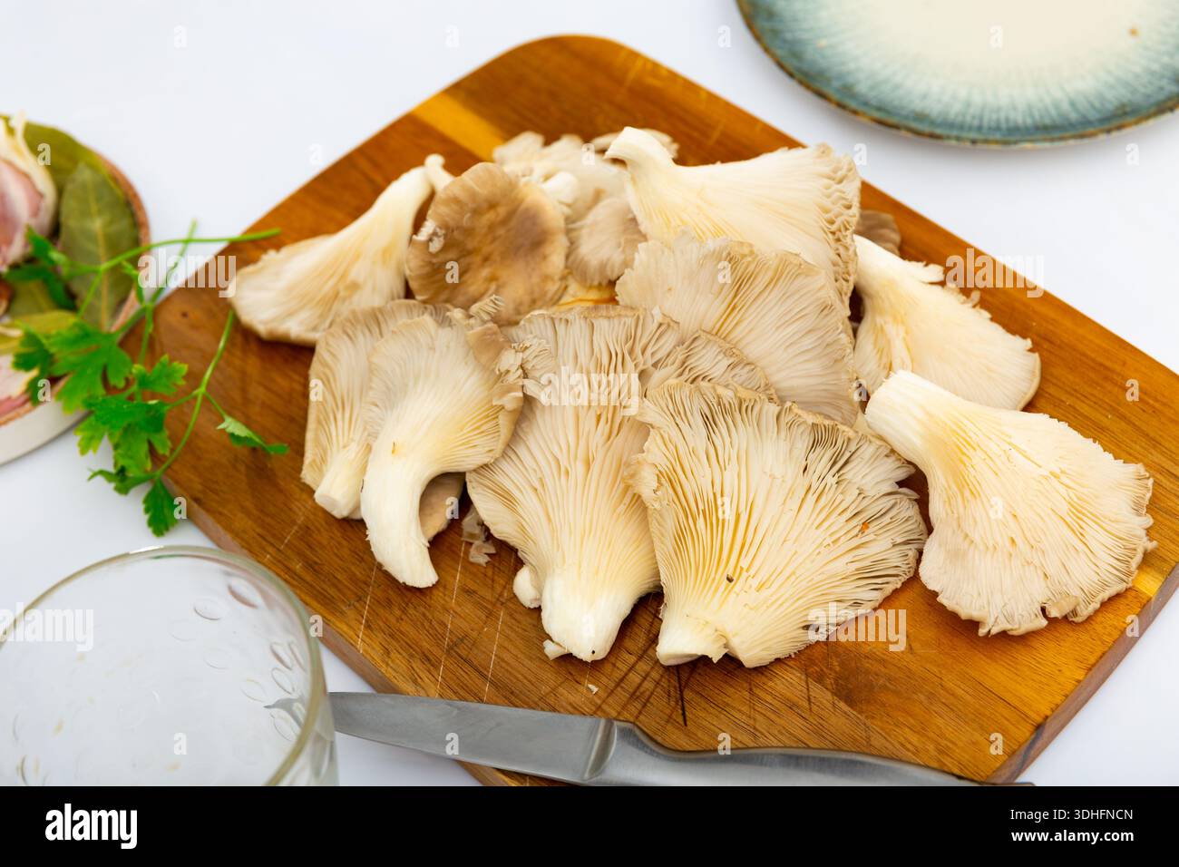 Es gibt einen Haufen roher Austernpilze auf dem Schneidebrett. Stockfoto