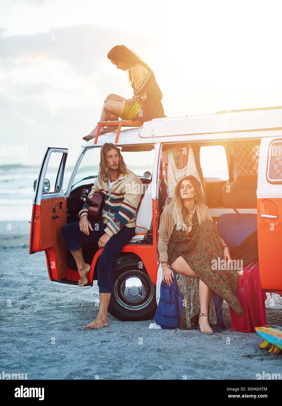 Menschen, Freunde und entspannen Sie sich mit einem Caravan am Strand für Roadtrip-Abenteuer oder Outdoor-Reise zusammen. Hipster, Gruppe oder Reisende mit Fahrzeug für Stockfoto