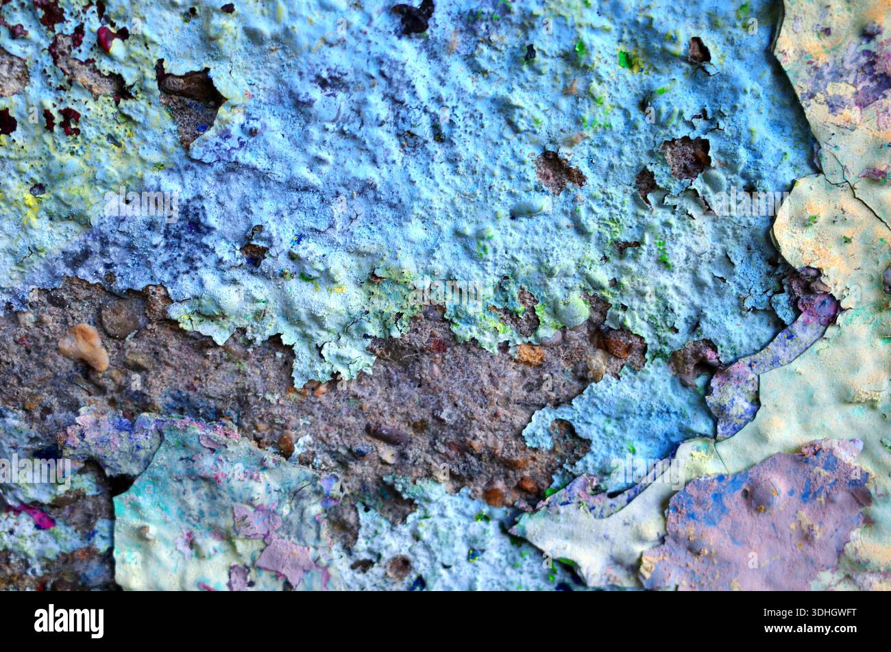 Eine Nahaufnahme einer Wand mit Schichten abblätternder Farbe in Blau- und Grüntönen. Die Textur ist rau und ungleichmäßig, mit Flecken aus freiliegendem Braun und Stockfoto