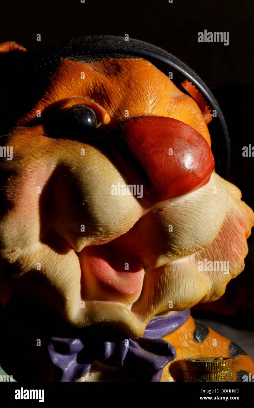 Eine farbenfrohe Figur mit roter Nase und Hut hebt sich vor einem dunklen Hintergrund hervor. Licht trifft auf die Details der Figur. Stockfoto