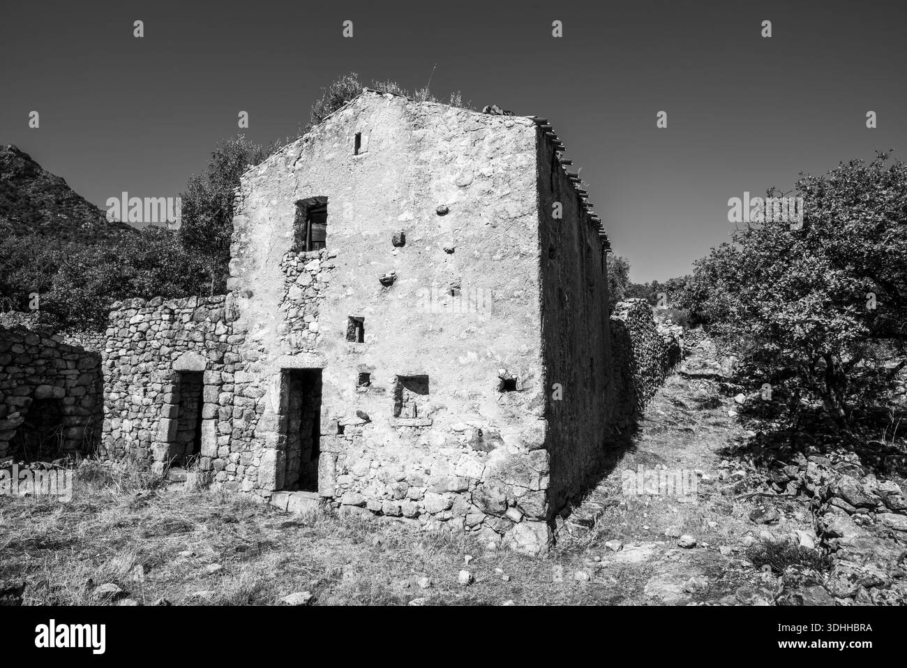 Schwarz-weiß-Blick auf verlassenes ländliches Steinhaus in Korsika Frankreich. Starke Geometrie und raue Oberflächen betonen Zerfall, Gedächtnis und Belastbarkeit in a t Stockfoto