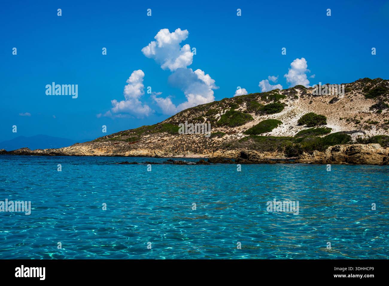 Felsige Küste und kristallblaues Wasser unter dramatischen Wolken in Calvi, Korsika, Frankreich. Eine weite mediterrane Meereslandschaft, die Raum, Reinheit und tim ausdrückt Stockfoto