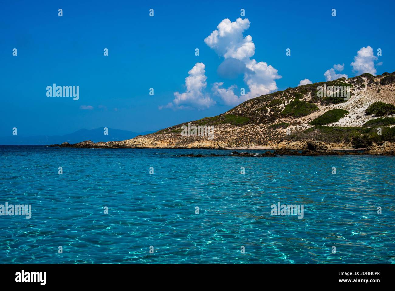 Großer Blick auf das türkisfarbene Mittelmeer mit Blick auf einen felsigen Hügel in der Nähe von Calvi, Korsika, Frankreich. Klarer Horizont, lebendige Wasserstrukturen und Sommerlicht e Stockfoto