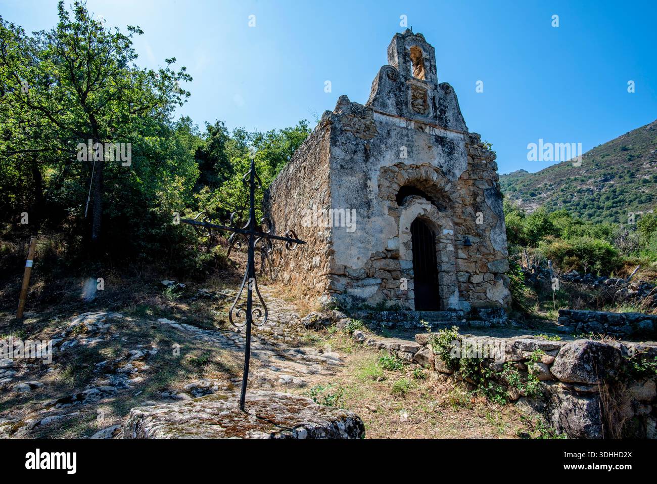 Der alte Steinweg führt zu einer abgeschiedenen Kapelle in den Hügeln in der Nähe von Corte, Korsika, Frankreich. Eine ruhige mediterrane Szene, die Zeitlosigkeit und Tradition ausdrückt Stockfoto