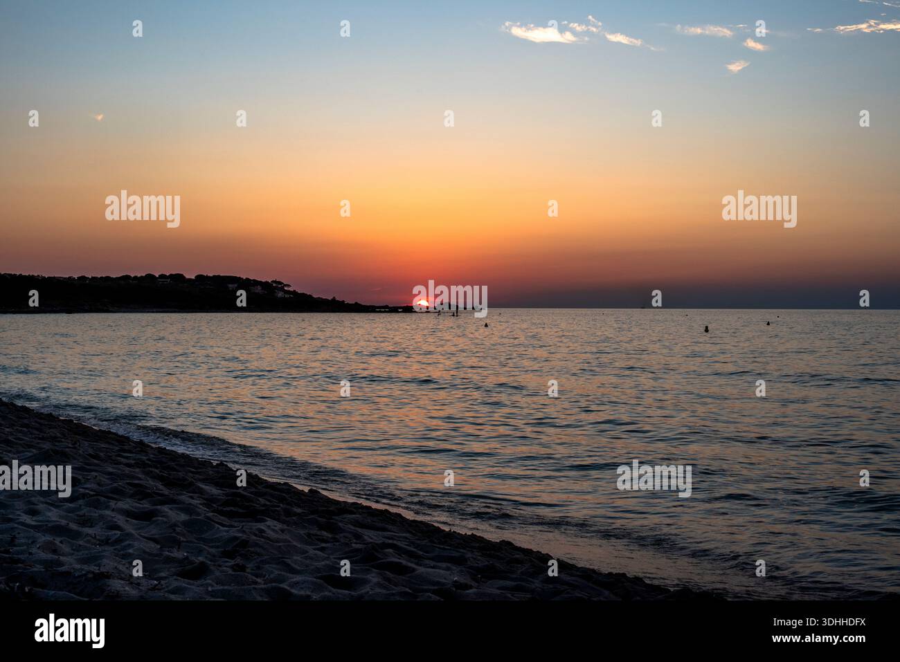 Goldene Sonne, die sich bei Sonnenuntergang über sanften Wellen an einem korsischen Strand, Frankreich, spiegelt. Warme Töne und ruhige Bewegungen sorgen für Balance, Entspannung und zeitlose Atmosphäre Stockfoto