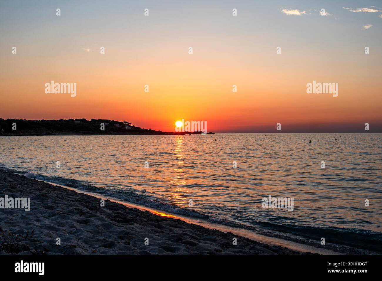 Sonnenuntergang über einem ruhigen Mittelmeer mit warmen Reflexen an einem Sandstrand in Korsika, Frankreich. Eine friedliche Küstenlandschaft, ideal für Reisen, Wellness Stockfoto