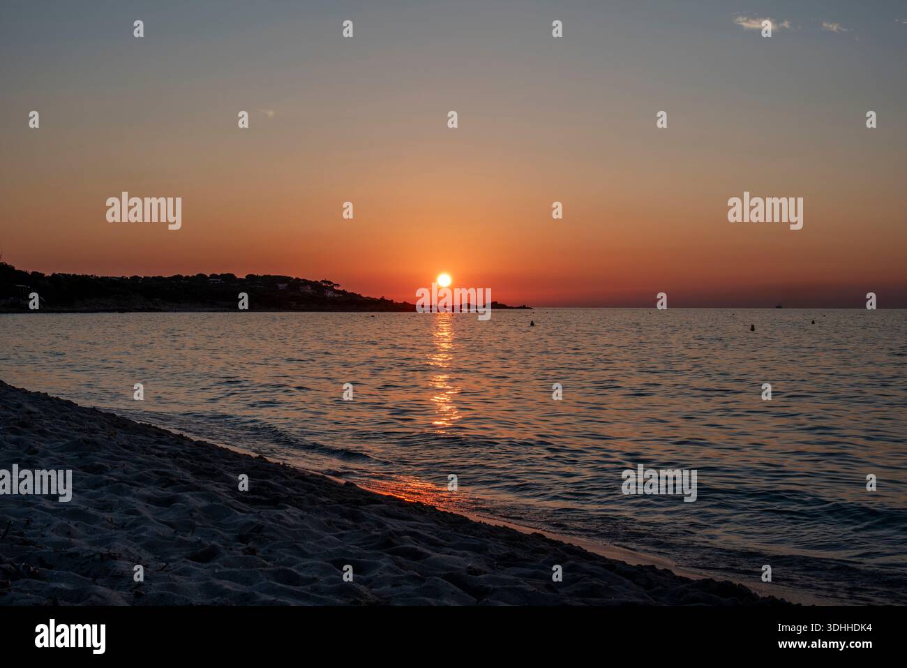 Sonnenuntergang über dem Mittelmeer mit einer warmen Reflexion, die sich zum Ufer in Korsika, Frankreich, erstreckt. Eine ruhige Küstenszene, die ein Gleichgewicht ausdrückt, CA Stockfoto