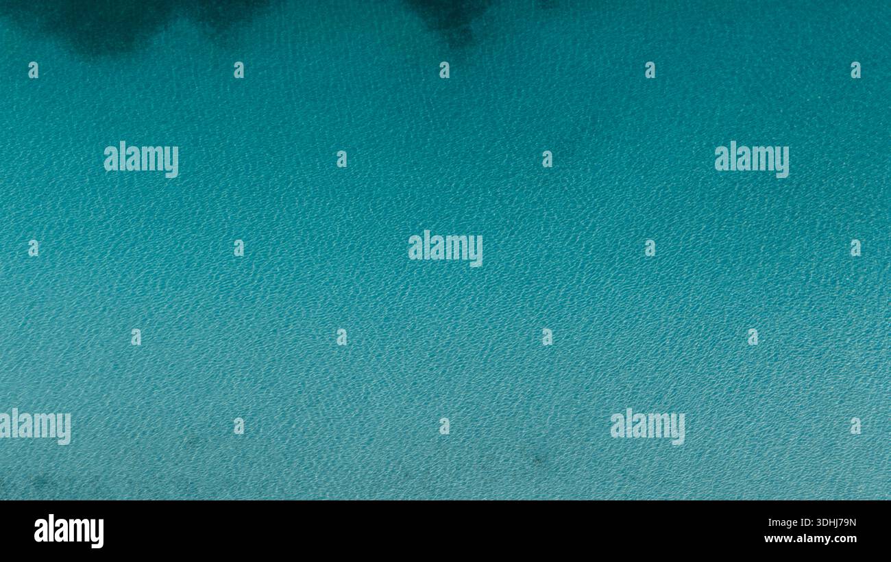 Luftaufnahme, die die Textur des tiefblauen und klaren Salda-Sees zeigt. Minimalistischer und friedlicher Hintergrund mit leichten Wellen auf der Wasseroberfläche. Stockfoto