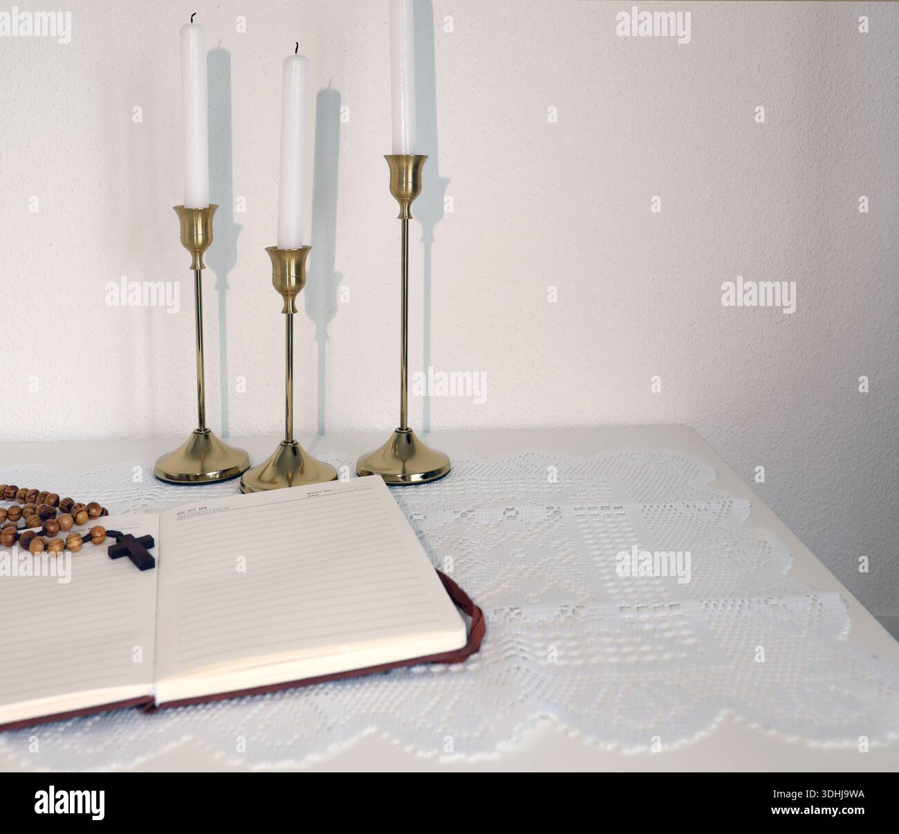 Katholische Ecke zu Hause. Hölzerne Rosenkranzperlen, Kreuz und Gebetsbuch. Glaube, Symbole und Traditionen. Stockfoto