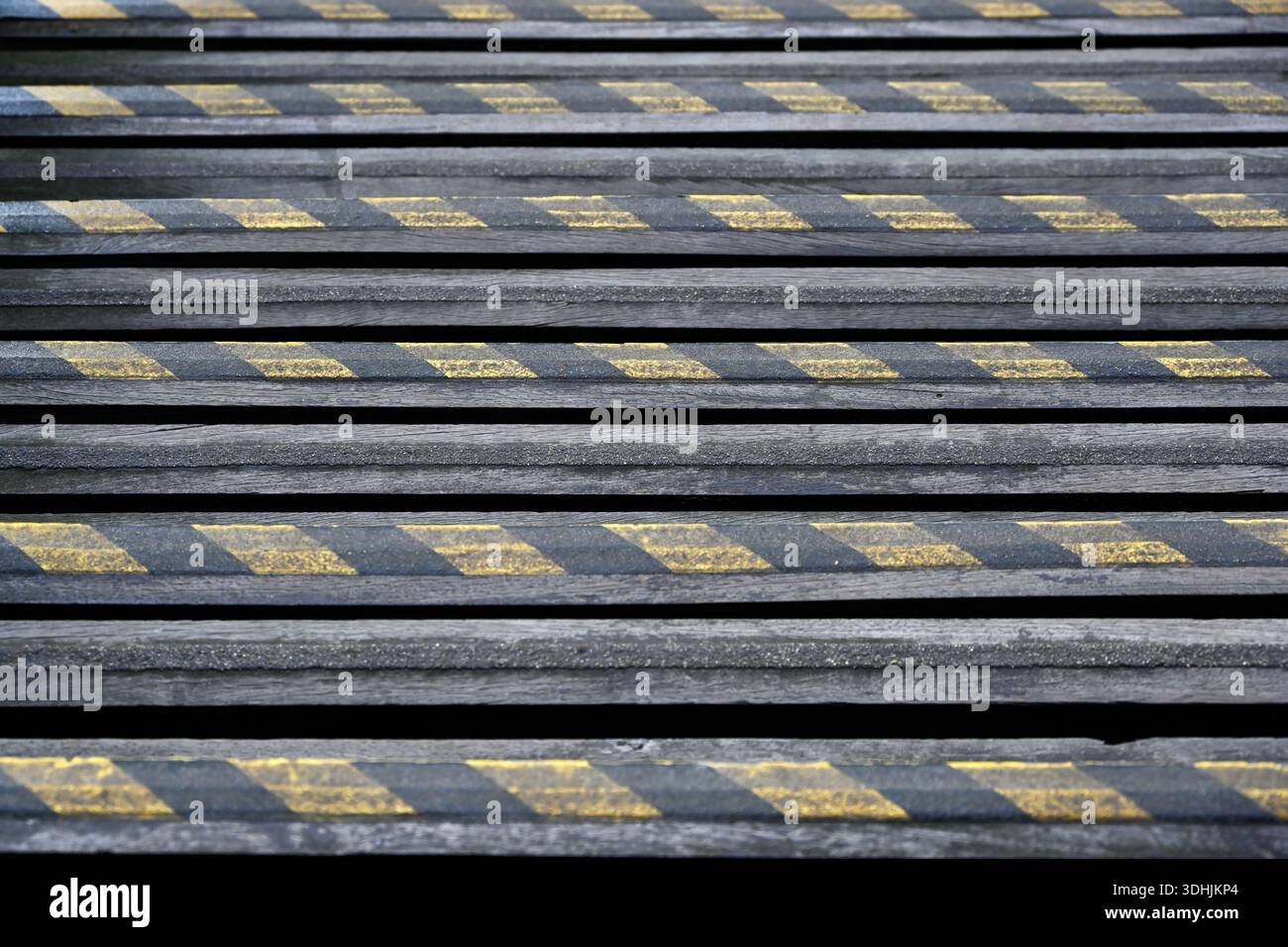 Abgenutzte gelbe und schwarze Warnstreifen auf alten Stufen als Hintergrund Stockfoto