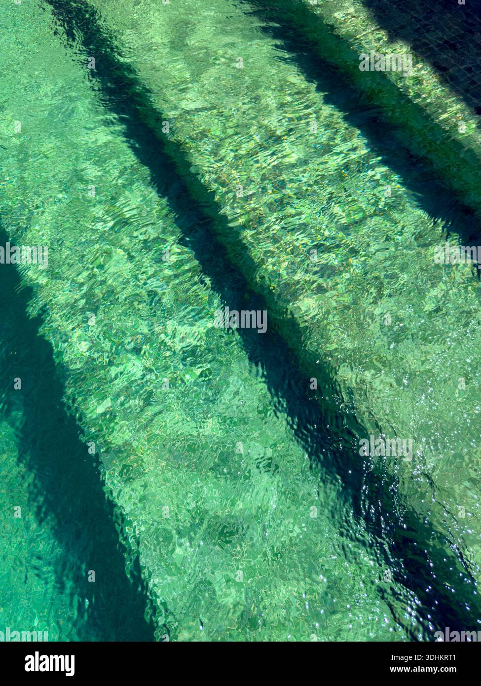 Abstrakte Lichtmuster auf grün gekacheltem Schwimmbadboden mit plätschernden Wasserreflexionen: Phillip Roberts - Smartphone-aufgenommenes Stockfoto