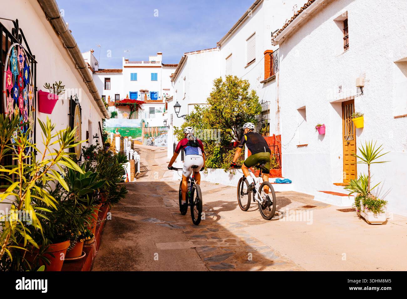 Radfahrer auf ihrem Weg durch das Dorf. Cartajima, Málaga, Andalucía, Spanien, Europa Stockfoto