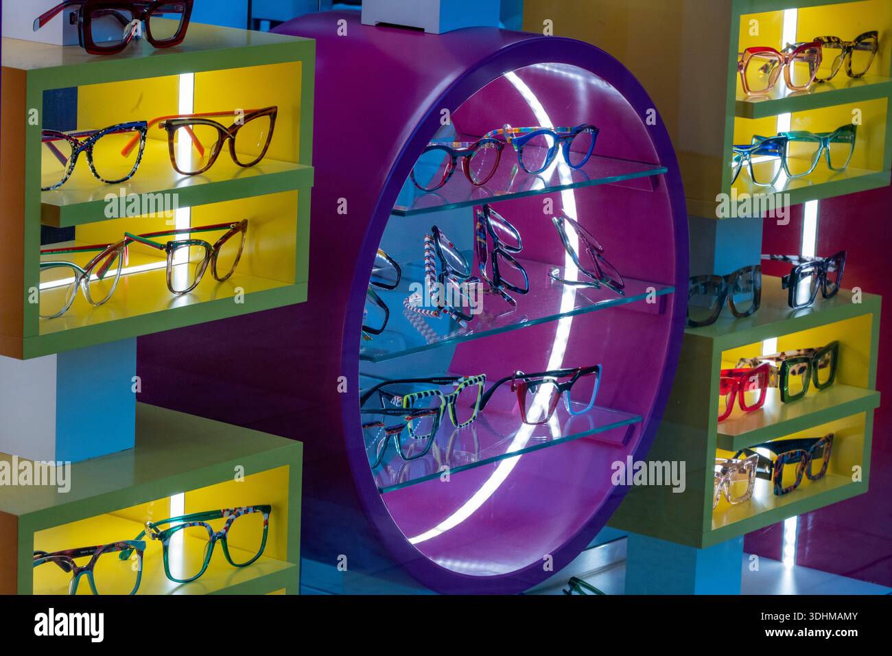 Brillen und Brillen auf einem farbenfrohen, auffälligen Ausstellungsstand in einem Optikergeschäft im Stadtzentrum von Cardiff, Wales, Großbritannien Stockfoto