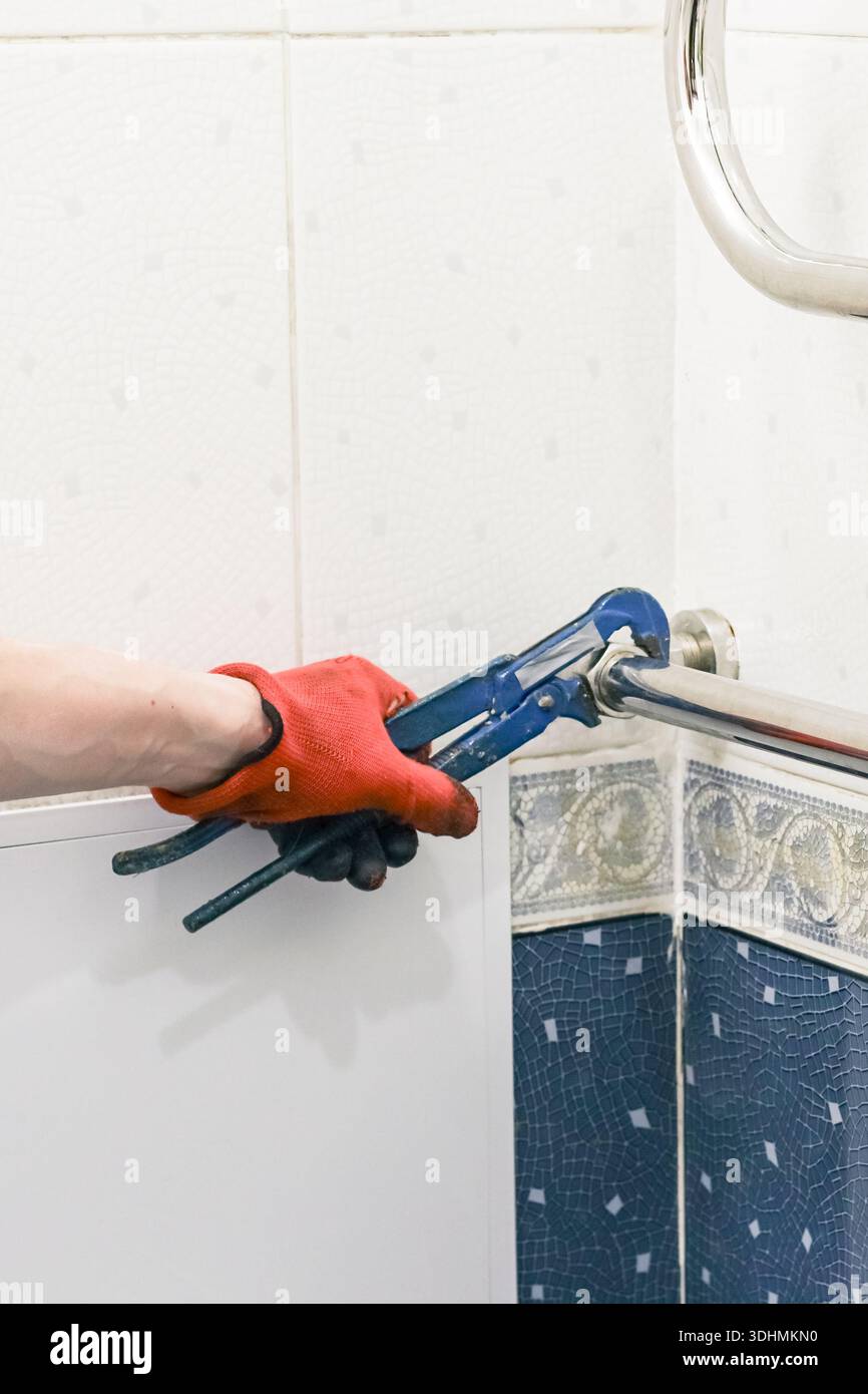 Klempner-Einstellvorrichtung mit schmutzigem Schraubenschlüssel in der Renovierungsszene des Badezimmers mit blauem Mosaikrand Stockfoto