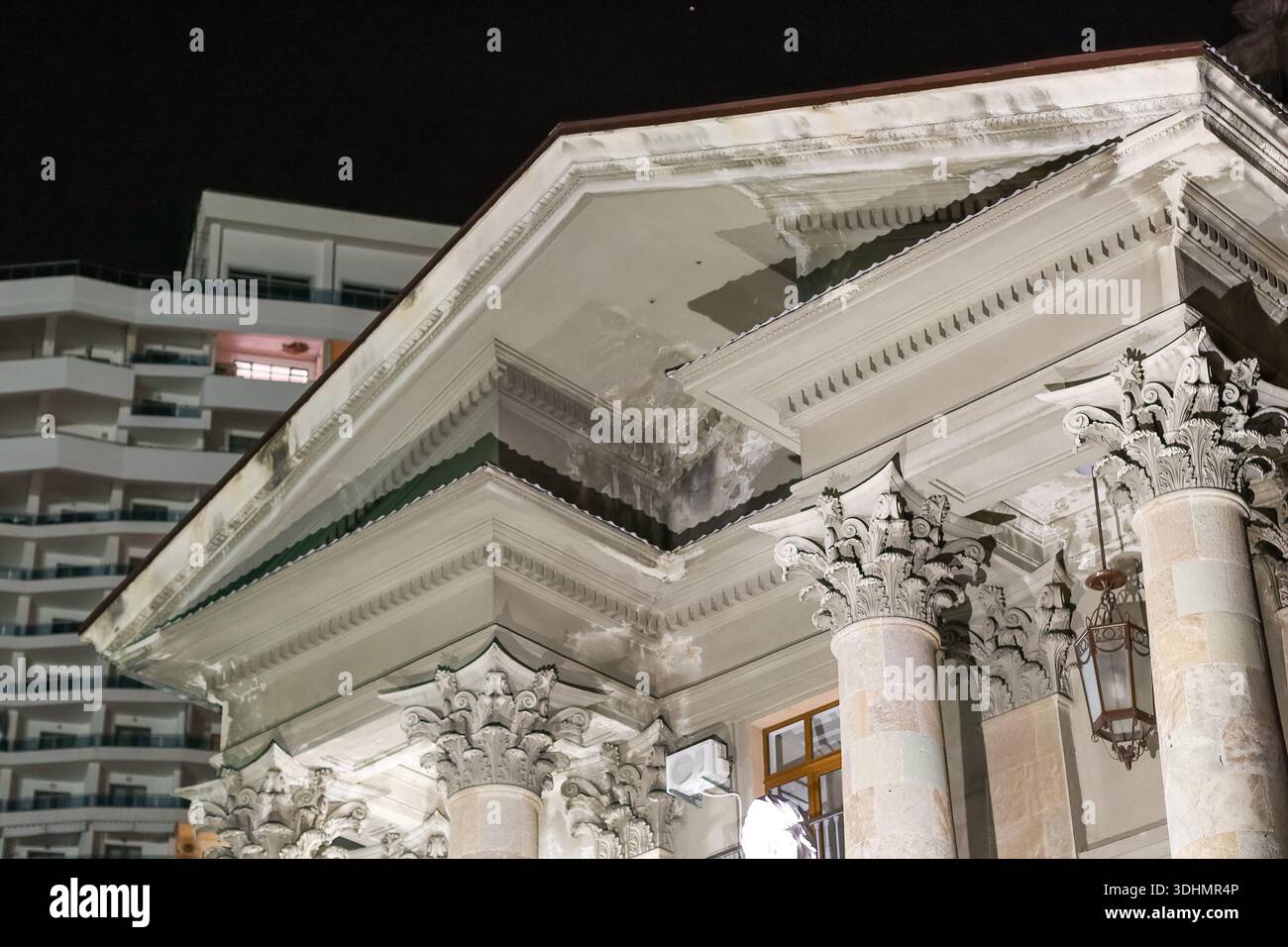 Korinthische Steinsäulen und kunstvoller Giebel des historischen Gebäudes, beleuchtet bei Nacht Stockfoto