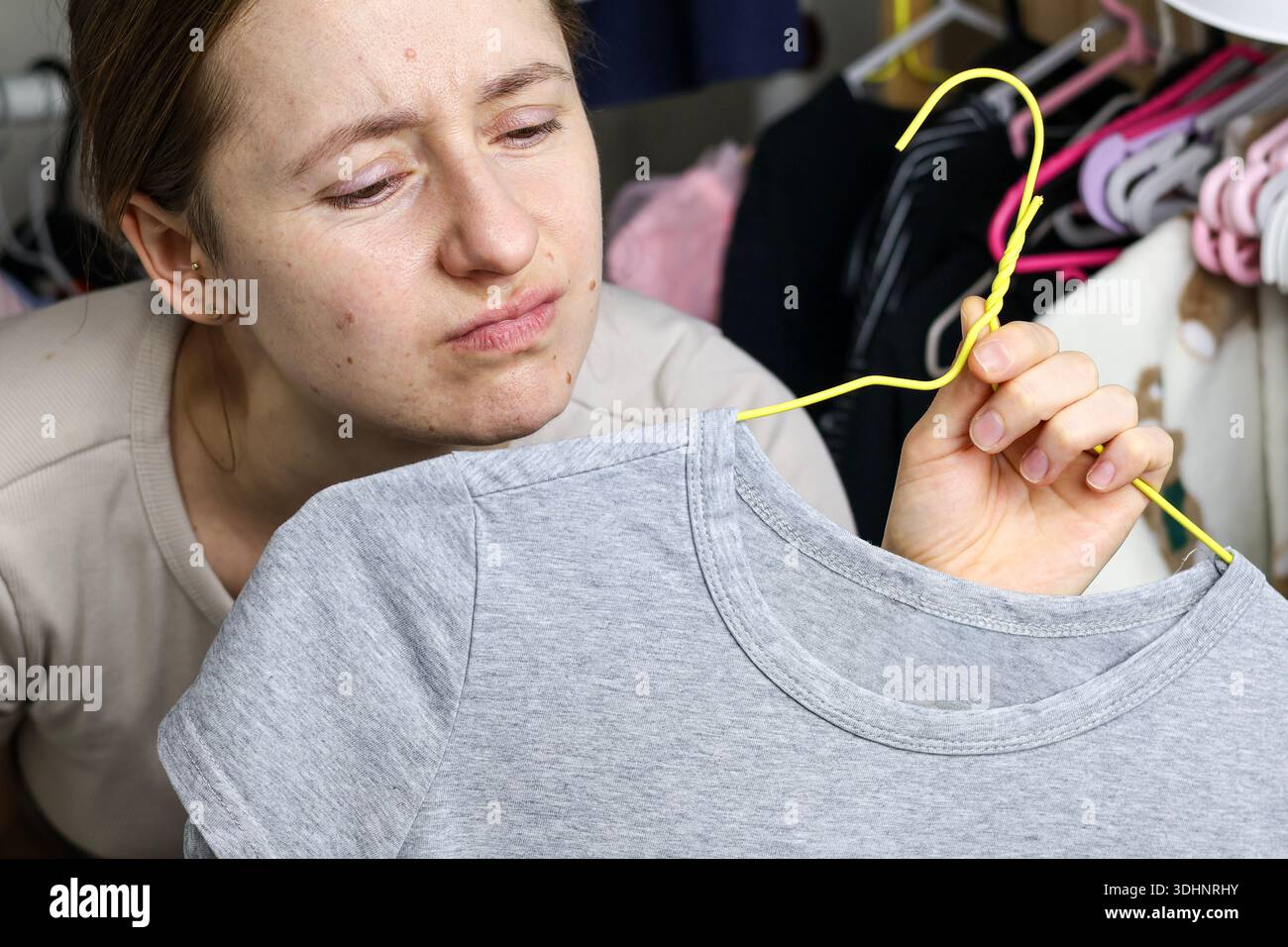 Seoul, Südkorea — 23. Janiary 2026: Eine Frau sieht sich ein Kleidungsstück an, während sie zu Hause in der Nähe einer Garderobe steht Stockfoto