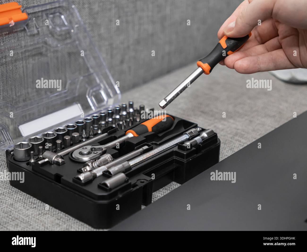 Nahaufnahme einer Hand, die einen austauschbaren Schraubendreher-Einsatz aus einem organisierten Werkzeugkasten auswählt, um Präzision und Bereitschaft für verschiedene Wartungsarbeiten zu betonen Stockfoto