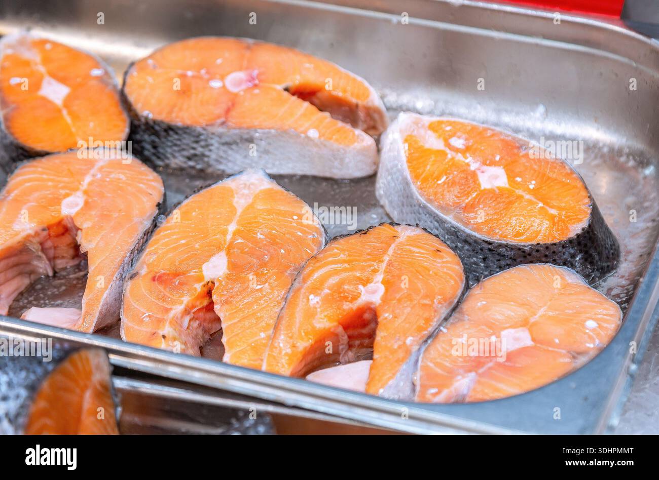 Steaks mit frischem Lachsfisch auf der Theke. Roher roter Fisch zum Verkauf. Fisch- und Meeresfrüchtegeschäft. Showcase mit gekühltem rotem Fisch im Lebensmittelgeschäft Stockfoto