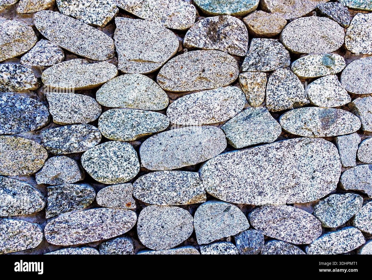 Raue Steinwand als kreative Hintergrundstruktur. Natursteinmauerwerk mit unebenen Nähten. Steinmauer Hintergrund Stockfoto