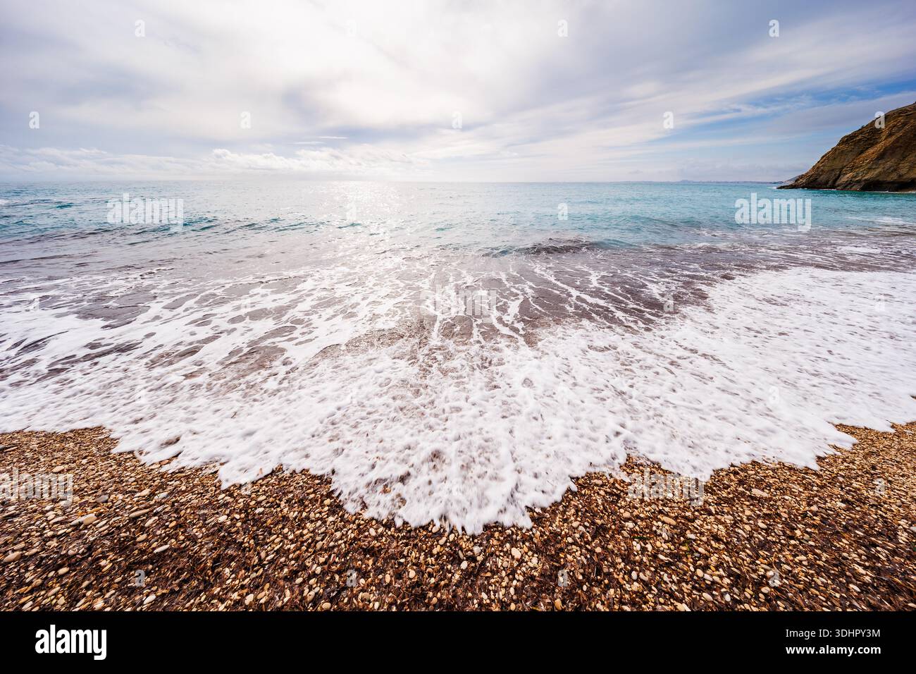 White Sea Foam, Der Über Dem Kieselstrand Gespült Wird Stockfoto