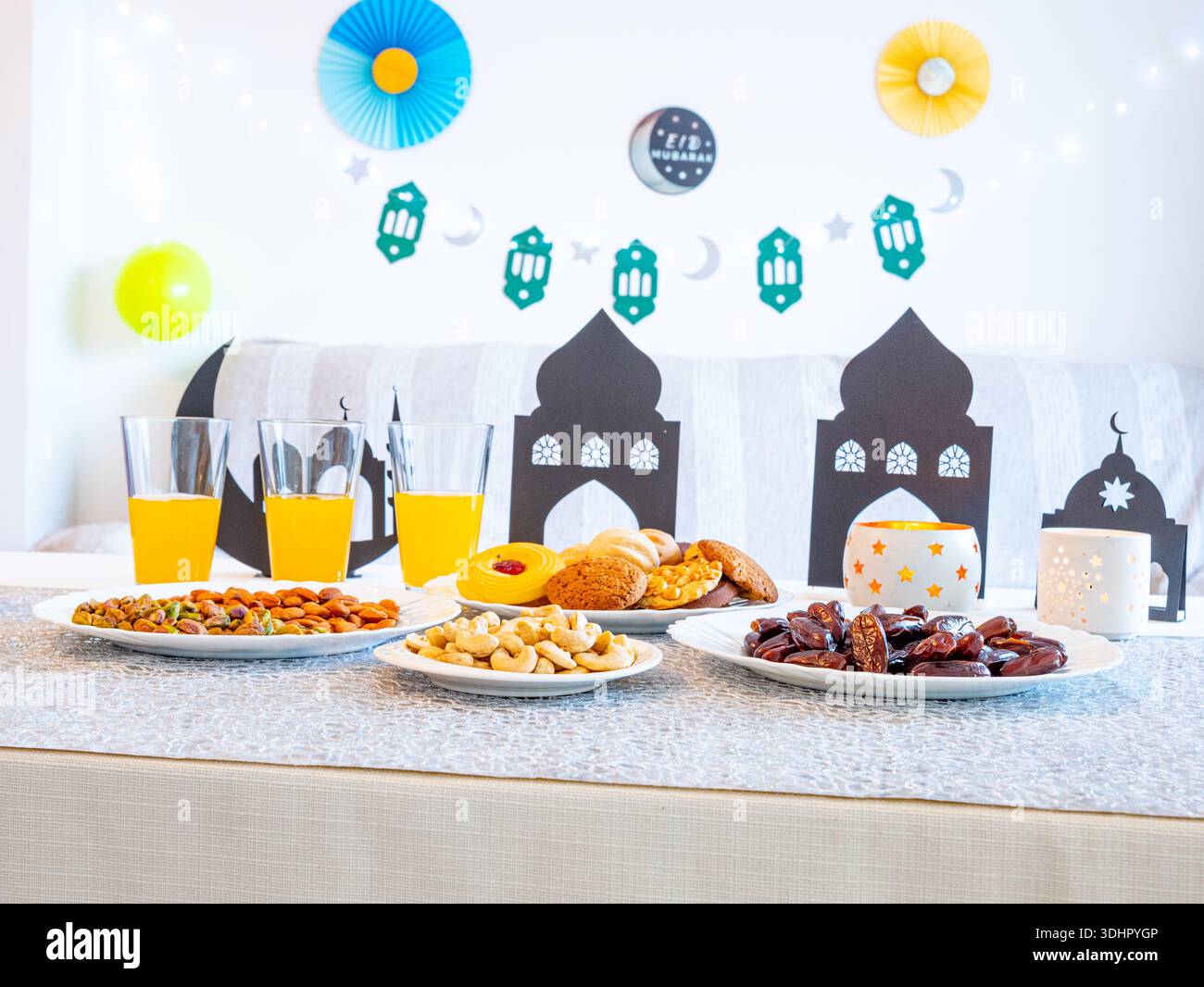 EID Mubarak-Tisch mit Ramadan-Süßigkeiten, Datteln, Nüssen und festlicher Einrichtung Stockfoto