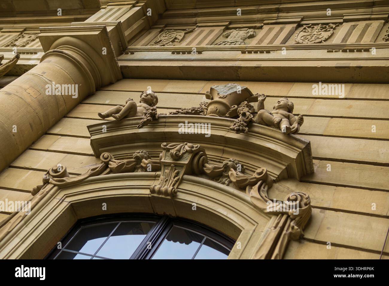 Flacher Blick auf ein kunstvoll verziertes Barockportal mit skulpturalen Putten und reicher Steindekoration an der Fassade der Residenz Würzburg in Deutschland. Stockfoto