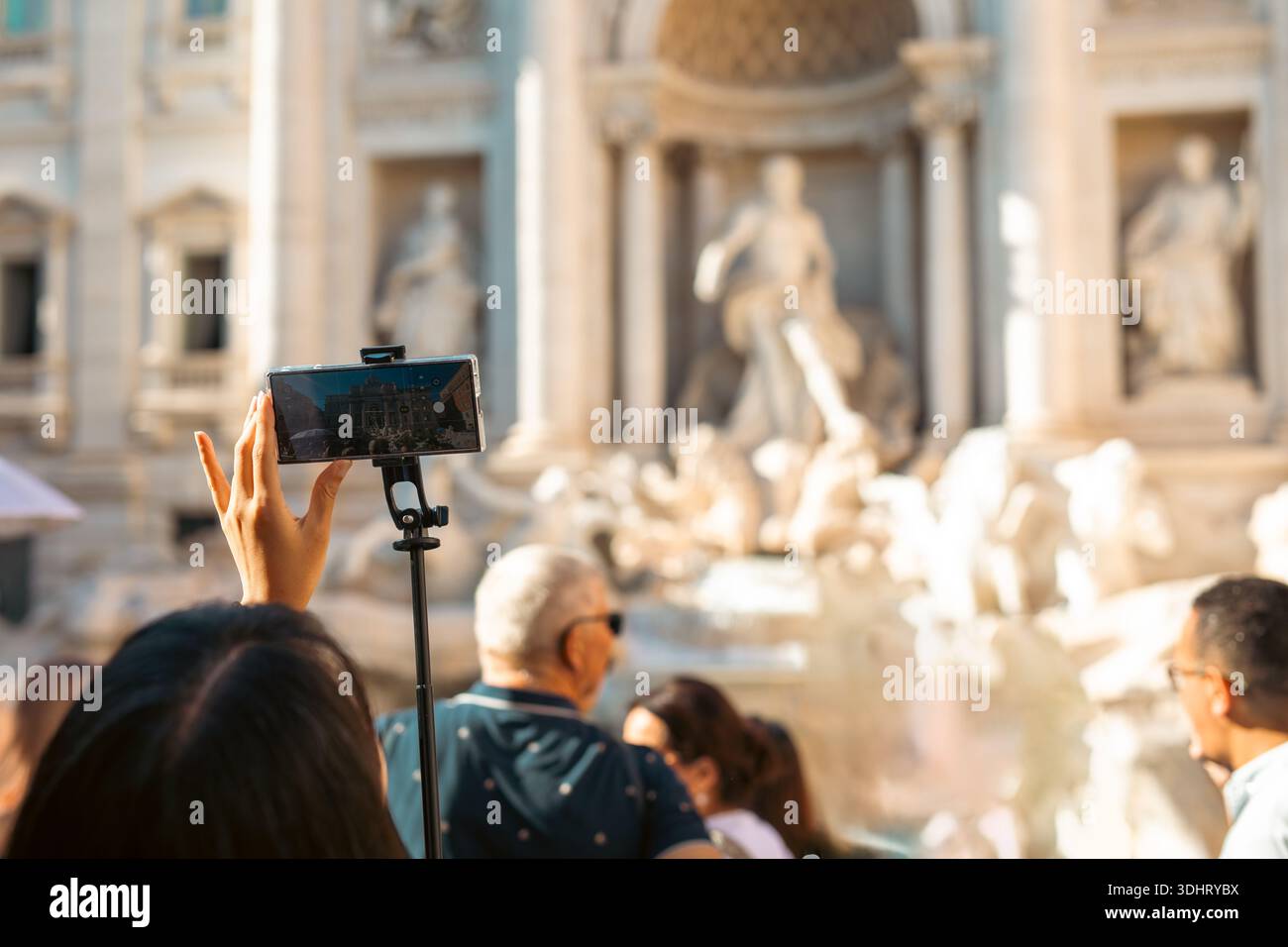 Touristen halten das Wahrzeichen mit Selfie-Sticks an einer geschäftigen historischen Stätte fest. Rom Italien Stockfoto