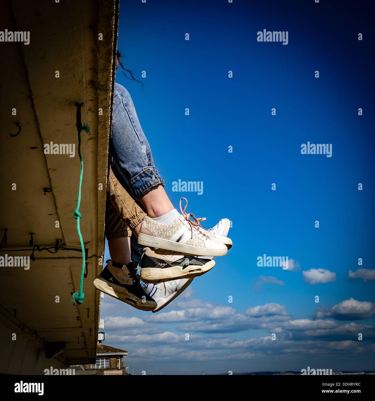 Füße hängen über einer Dachkante Stockfoto