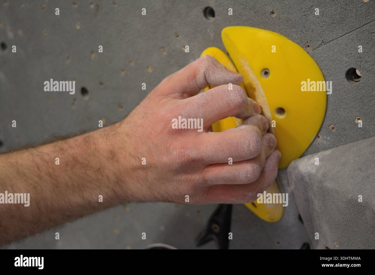Nahaufnahme einer Kreidehand, die eine gelbe Bouldersperre greift Stockfoto
