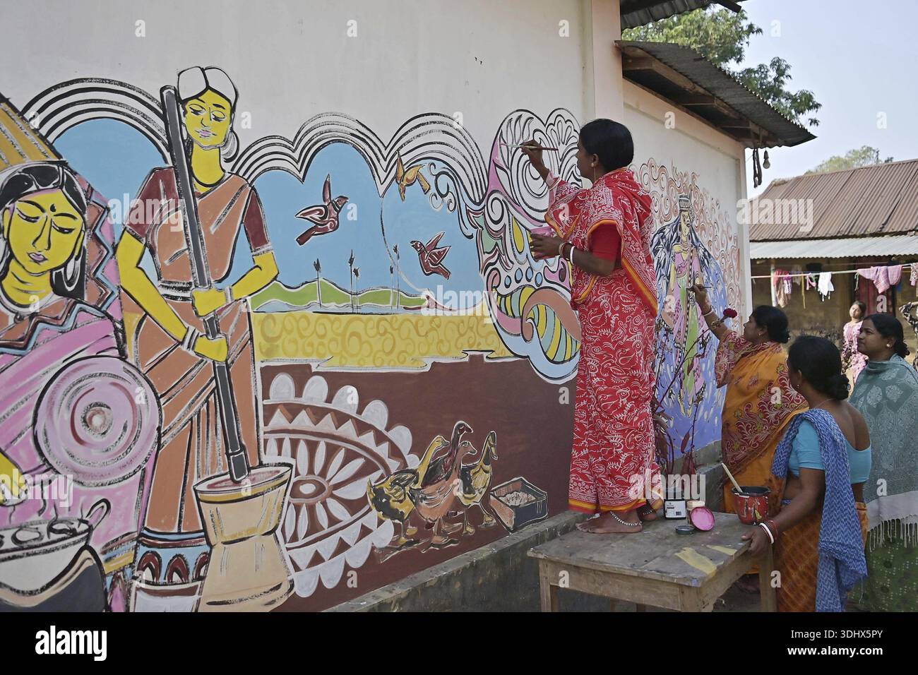 Agartala, Tripura, Indien, 12.01.2026: Frauen malen Alpona auf dem Boden vor dem Hindu-Festival Makar Sankranti im Dorf Lankamura in Agartala. Stockfoto