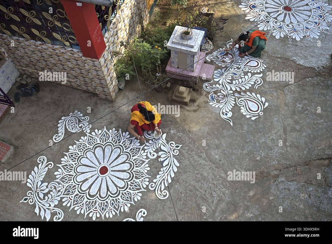 Agartala, Tripura, Indien, 12.01.2026: Frauen malen Alpona auf dem Boden vor dem Hindu-Festival Makar Sankranti im Dorf Lankamura in Agartala. Stockfoto