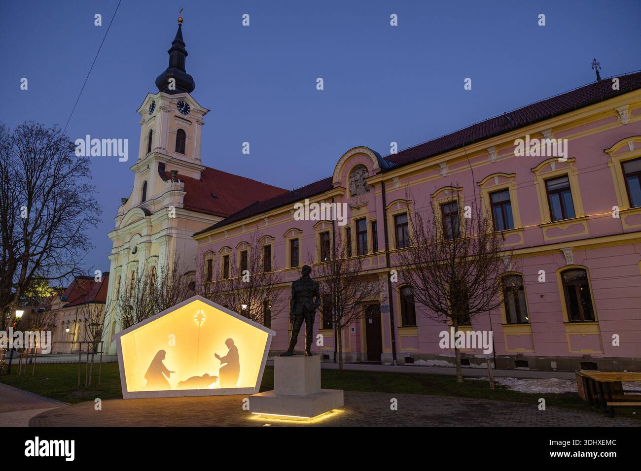 Eine ruhige Abendszene in einer europäischen Stadt mit einer leuchtenden, sternenbeleuchteten Krippe in einer Polygon-Laterne vor einem rosafarbenen historischen Gebäude mit einem Stockfoto