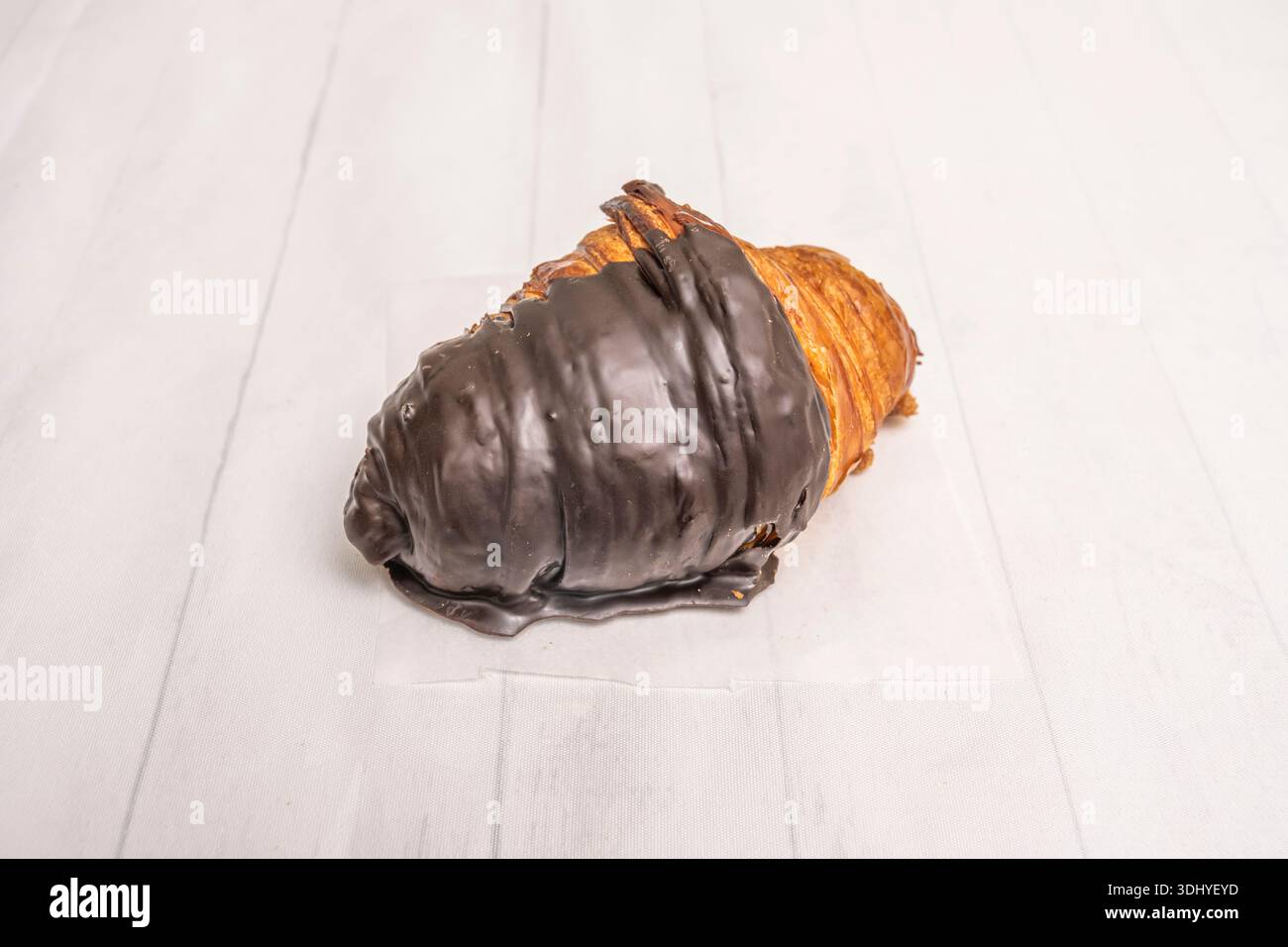 : Das Bild eines exquisiten Mandelcroissants, bedeckt mit einer knusprigen Schicht aus Mandelblättchen und Zucker, bestreut mit dünnen Nussscheiben Stockfoto