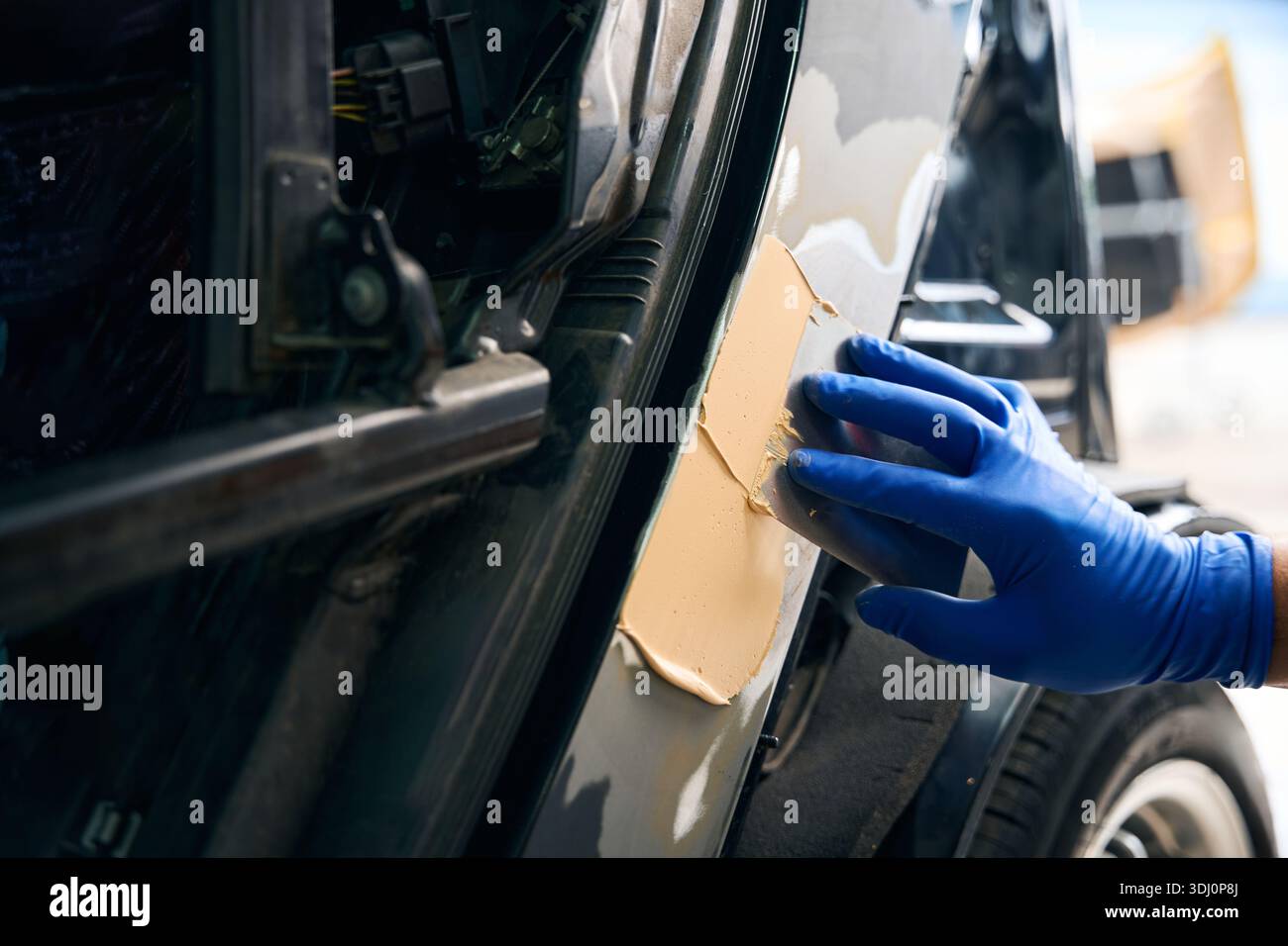 Der Servicetechniker verwendet Kitt in der Autowerkstatt Stockfoto