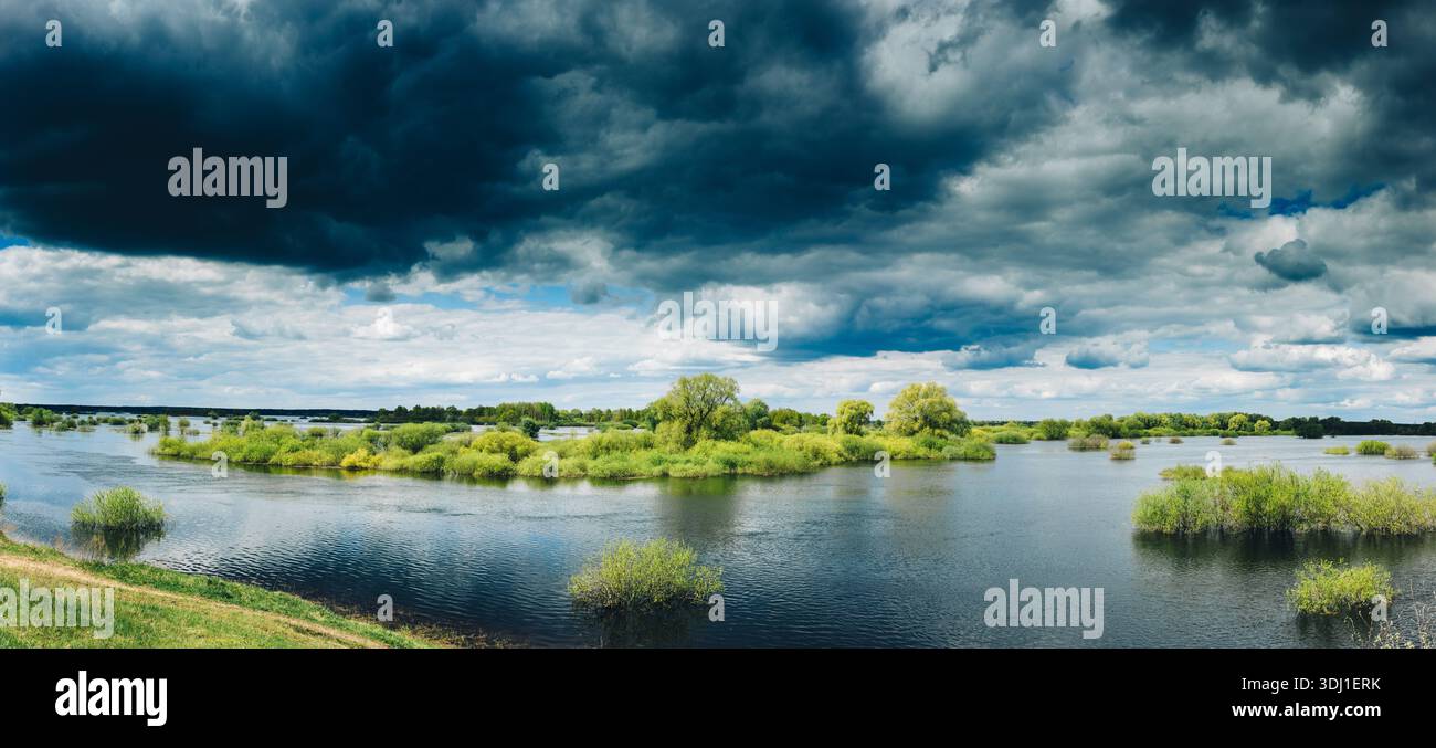 Üppige Flusslandschaft – Spring River mit alten Bäumen und dramatischem Blick auf den bewölkten Himmel Stockfoto