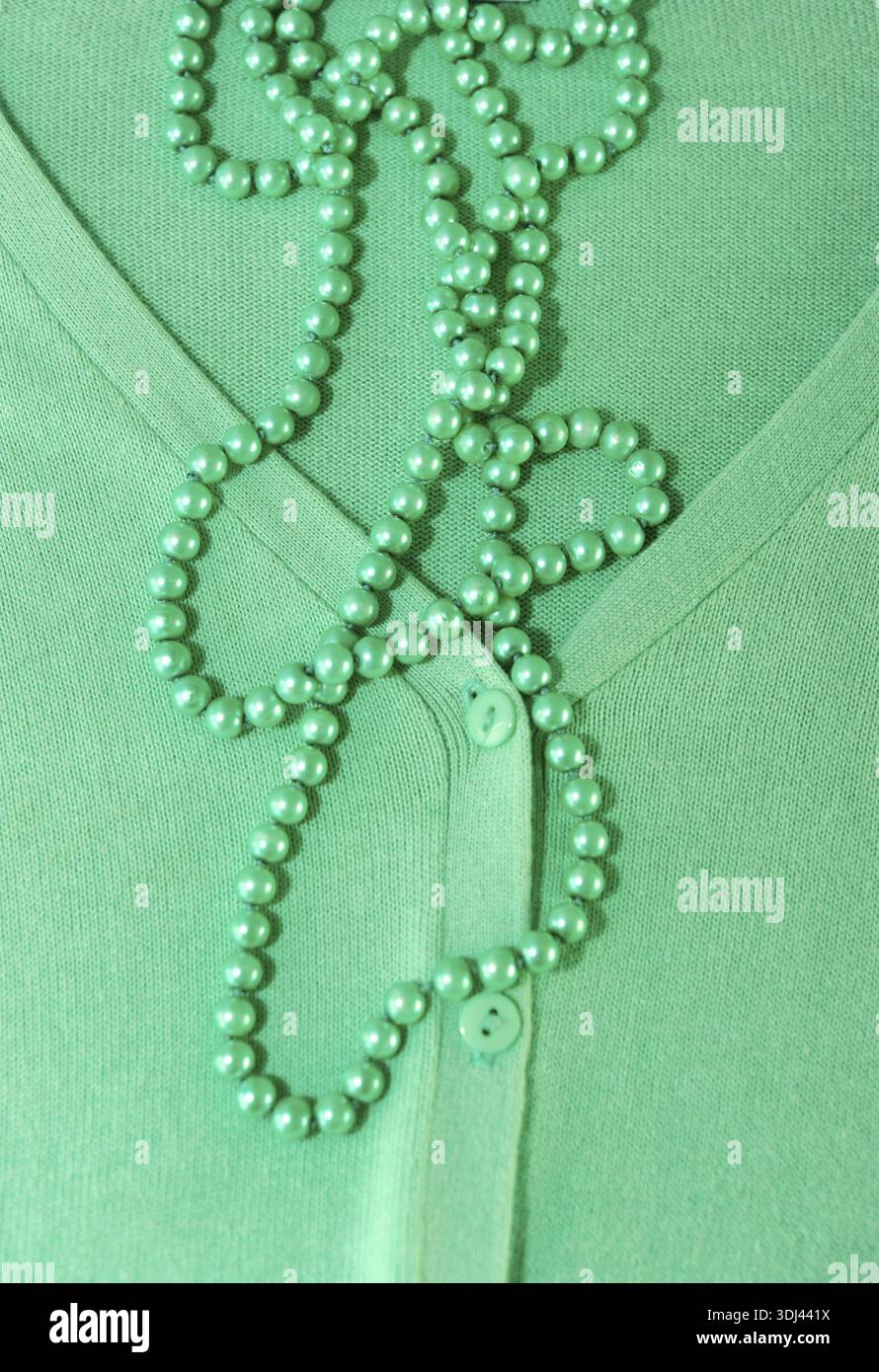 Grüne Perlenperlen auf einem grünen Pullover mit Knöpfen, Eleganz von Grün und womenÂ Modekonzept, grüne Farbe und Frühling Stockfoto