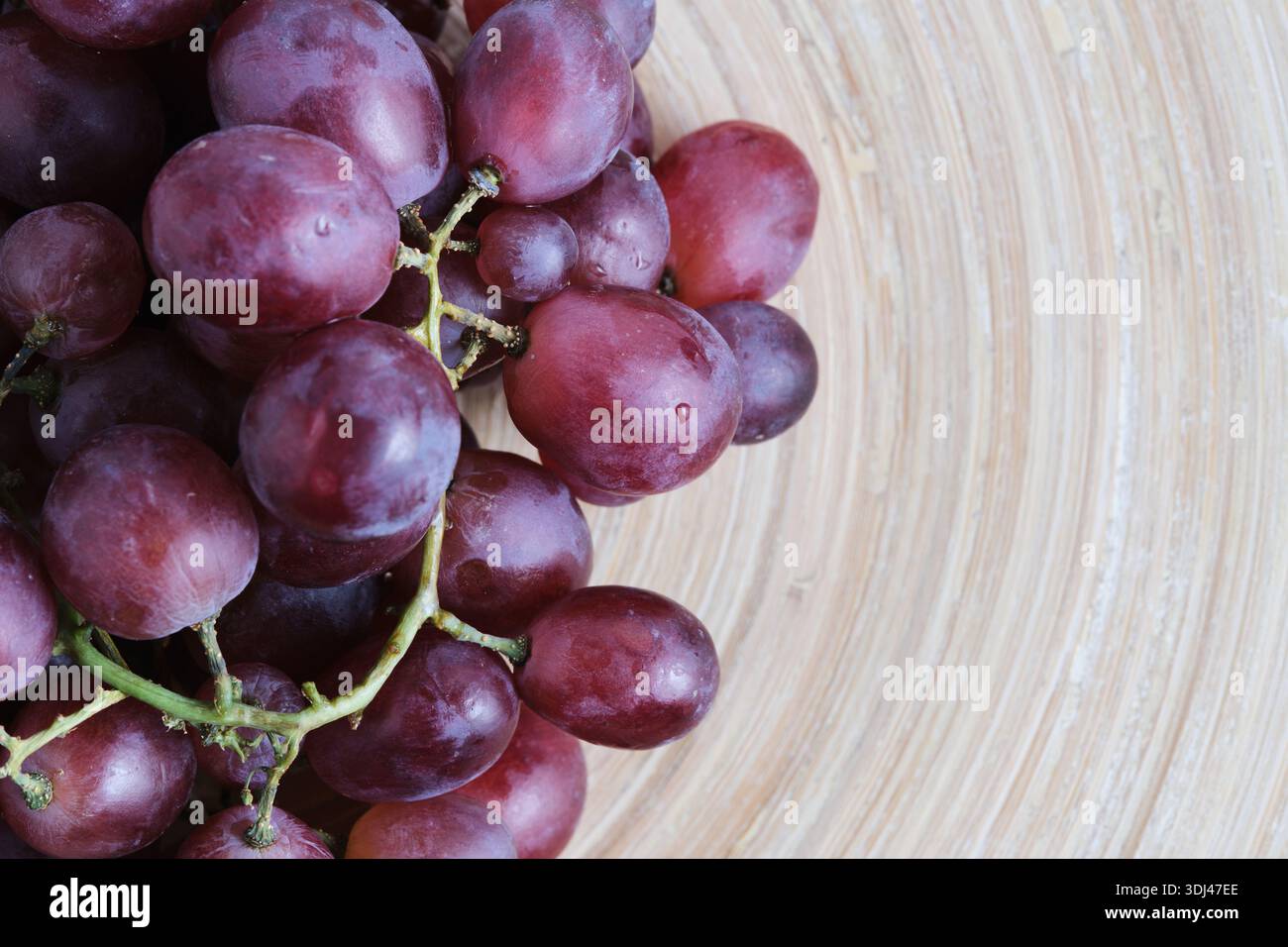 Frische rote Trauben mit Wassertropfen in einer Holzschale Stockfoto