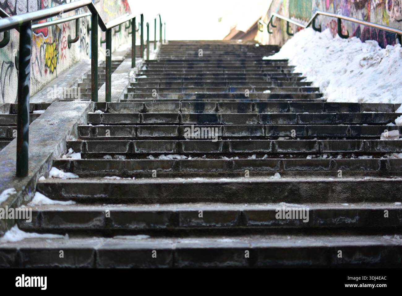 Betontreppen im Freien mit Eis und Schnee bedeckt, städtische Umgebung. Leere Treppe mit Metallgeländern, kaltes Wetter, städtische Infrastruktur Stockfoto