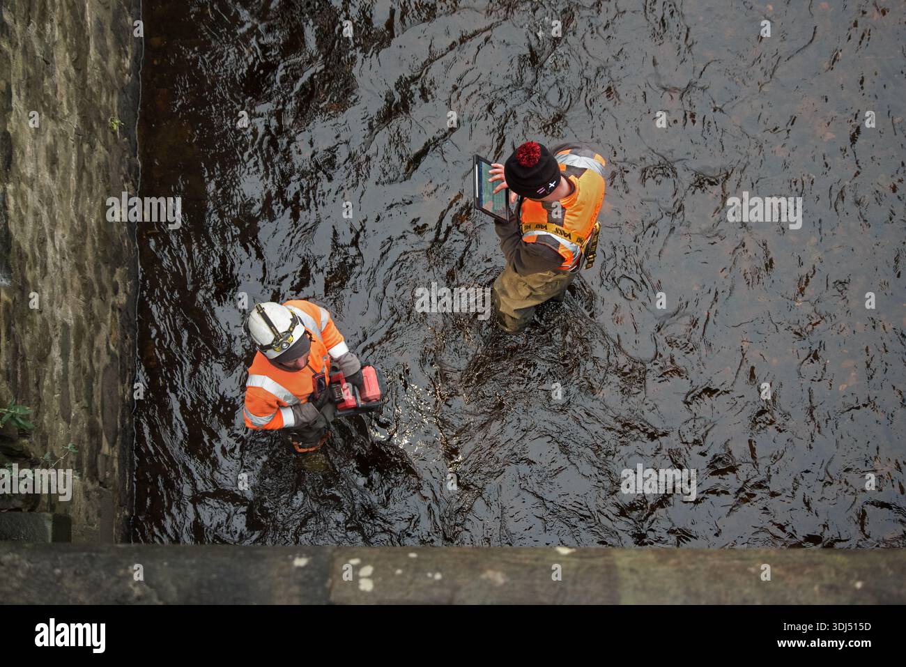Männer, die im Wasser von Leith stehen und Daten auf einem Tablet in Canonmills, Edinburgh, Schottland, eingeben. Stockfoto