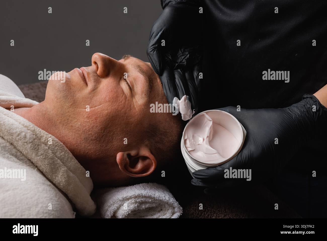 Nahaufnahme des Mannes, der Gesichtsmaske zur Faltenkorrektur und Verjüngung, professionelle Hautpflege und Wellness-Behandlung erhält. Stockfoto