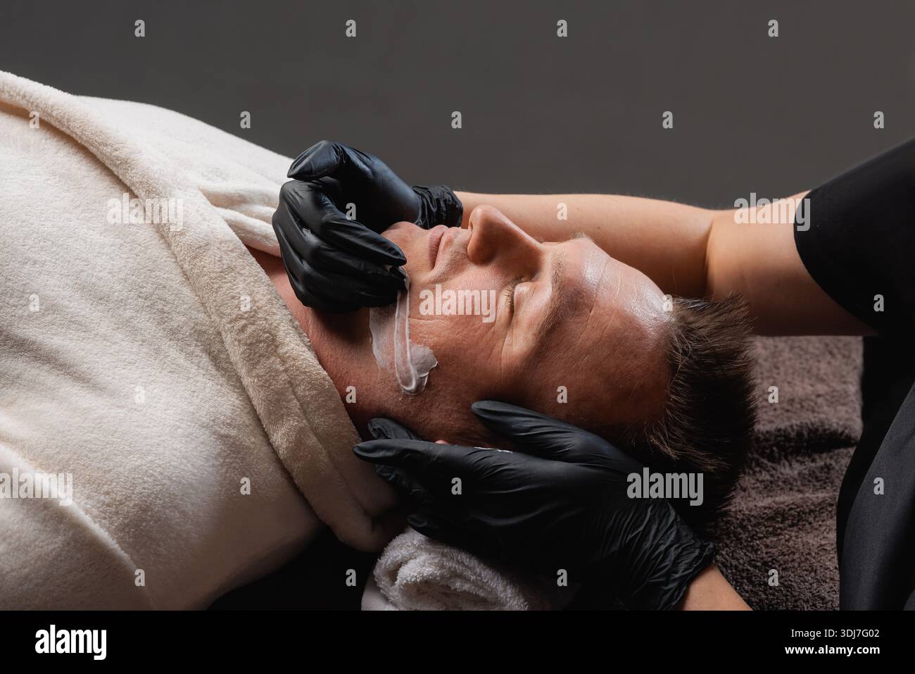 Professionelle Anwendung der Gesichtsmaske für Männer, Faltenkorrektur, Anti-Aging und Verjüngung Spa Hautpflege Behandlung. Stockfoto