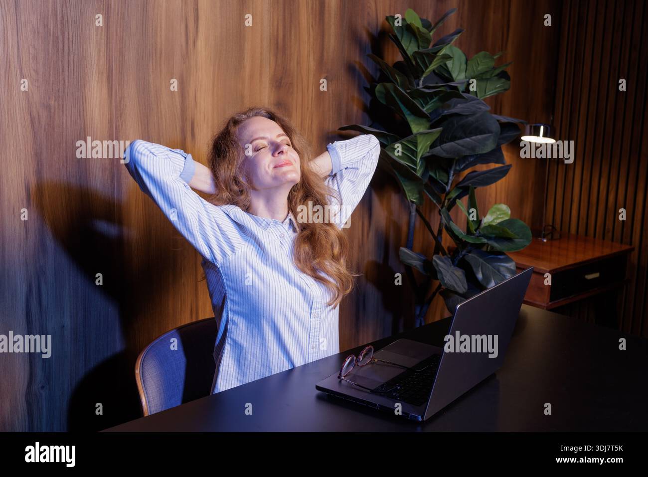 Entspannte Geschäftsfrau, die eine Pause am Arbeitsplatz macht, sich mit geschlossenen Augen zurücklehnt, nach der Arbeit Erleichterung genießt, Büroatmosphäre. Stockfoto