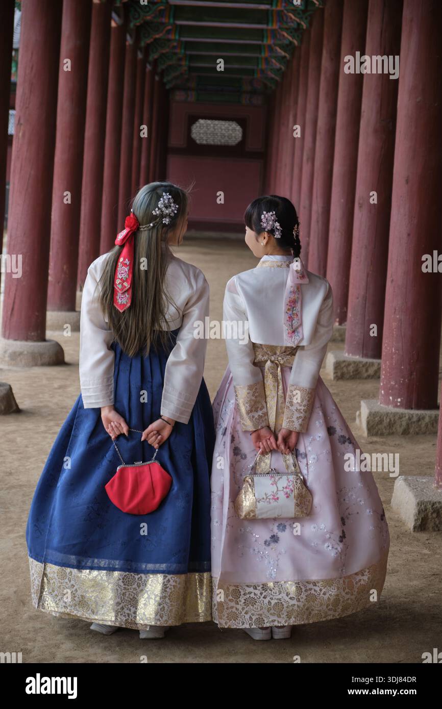 Seoul, Südkorea: Zwei Frauen im eleganten Hanbok, die gemeinsam durch den Palastkorridor im Gyeongbokgung Palace laufen Stockfoto